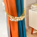Golden wire curtain tieback with white pearls on blue and orange drapery - Gold