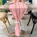 Pink chiffon table runner with delicate white ribbons on a rustic wooden dining table - Pink