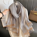 Detail of grey silk-like scarf featuring golden metallic stripes and fine woven texture - Light Gray