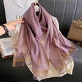 Dettaglio macro di sciarpa in seta viola con strisce dorate su maglia bianca - Malva