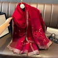 Détail d'une écharpe en soie et laine rouge avec bord doré brillant et broderie - 90*180cm / Bordeaux
