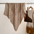 Close-up of floral print silk scarf with fine machine hemmed edges on a display stand - 68*68cm / Khaki