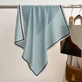 Detail of light blue silk scarf with black ring pattern draped on a metal rack - Aqua