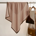 Detail of pink silk scarf with chain print and black contrast border on a wooden hanger - Coffee