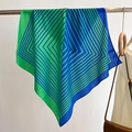 Detail of a geometric striped square scarf in green and blue hanging on a metal rod - Teal / 68*68cm