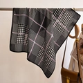 Detailed texture of houndstooth silk scarf with purple accents hanging on metal bar - Black