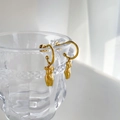 Boucles d'oreilles dorées avec pendentif buste féminin exposées sur un verre - Style de corps (Or)