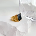 Detailed view of gold signet ring with black enamel top on textured white stone - US Size 6 / Gold Color Black