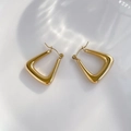 Macro shot of 18K gold geometric triangular hoop earrings on a minimalist white backdrop - Smooth Style