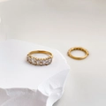 Gros plan de bagues minimalistes en or avec zircons carrés sur pierre blanche - US 6 / Style Large en Zircone