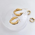 Detailopname van gepolijste gouden geometrische ruitvormige oorbellen op glas - 3D Ruit