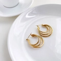 Dettaglio di orecchini a cerchio tripli dorati con design geometrico multistrato - Stile a Tre Strati