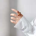 Close-up of a gold wavy fluid ring on a finger showing smooth liquid metal texture - US 6 / Bumpy Abstract Style
