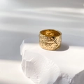 Detail of wide gold plated ring featuring irregular hammered texture on a stone stand - US 6 / Meteorite Crater Style
