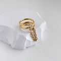 Dettaglio anello dorato a doppio strato con catena su roccia bianca minimalista - US 6 / Catena a Doppio Strato