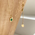 Dettaglio collana a catena dorata con pendente di smeraldo su supporto in legno - Smeraldo Ovale Piccolo