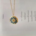 Dettaglio del ciondolo ottagonale dorato con smalto blu, motivo stella e zircone - Blu grigio