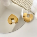 Macro shot of gold heart-shaped chunky earrings reflecting on a polished mirror surface - Heart Style / Gold