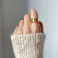 Close-up of a chunky gold irregular curved ring worn with a beige knitted sweater - US 6 / Curved Style