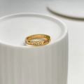 Close-up of 18K gold ring with clear zircons and starburst engraving on ceramic surface - US 6 / White Zirconia Style