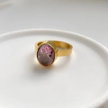 Detailed close-up of a gold ring featuring a large oval purple zircon in bezel setting - US 6 / Purple Zircon