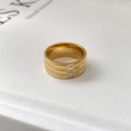 Detail van een brede 18k vergulde ring met drie verticale zirkonia-stenen en groeven - US 6 / Drie stenen