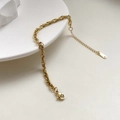 Dettaglio di un bracciale a catena piatta dorata poggiato su un vassoio di ceramica - Stile a Catena