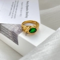 Detailed macro view of an emerald green gemstone ring on minimalist white packaging - US 6 / Emerald