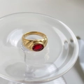 Macro detail of gold-plated wide ring with oval red gemstone and textured engraving - US 6 / Garnet Red