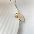 Close-up of minimalist gold ring with round zircon in a four-prong setting on white plate - US 6 / White Zirconia