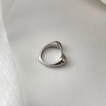 Dettaglio macro dell'anello a cuore in metallo lucido dal design organico e fluido - US 6 / Color Acciaio