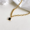 Macro shot of square black zircon pendant with golden chain and minimalist claw setting - Black Zircon