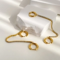 Dettaglio di orecchini a cerchio in zircone dorato con lunghe catene a nappa - Oro