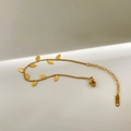 Dettaglio macro del bracciale a foglie dorate con incisione K18 su sfondo minimal - Bracciale