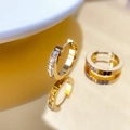 Macro detail of gold C-shaped earrings with baguette-cut cubic zirconia inlays - Half Row Zirconia Style