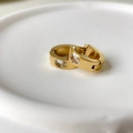 Close-up of gold C-shaped earrings with oval zircon insets and shell-style texture - Oval Zirconia Style