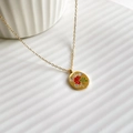 Macro-opname van de vergulde ovale hanger met bloemenemaille en sterrenaccenten - Roos