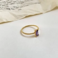 Vista dettagliata di uno zircone viola taglio smeraldo su un anello a treccia dorato - US 6 / Viola Chiaro