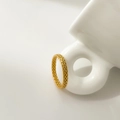 Detailed close-up of a gold woven texture ring resting on a white ceramic mug handle - US 6 / Fine Braided Style