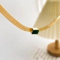 Dettaglio macro di una catena a serpente dorata con zircone verde sotto luce calda - Collana a Serpente Spessa Dorata (Zirconia Verde)