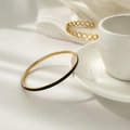 Detail van de minimalistische gouden armband met zwart emaille op zachte satijnen stof - Zwarte Emaille Stijl