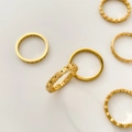Detailed top view of minimalist gold daisy and geometric rings on a beige background - US 6 / Daisy