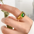 Primo piano di un anello in titanio dorato con zircone smeraldo rettangolare a castone - US 6 / Zircone verde rettangolare