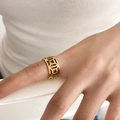 Makroaufnahme des vergoldeten hohlen geometrischen Rings mit filigranen Münzmustern - US 6 / Kupfermünze-Stil
