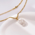 Detailed close-up of a gold baroque pearl necklace on a white ceramic dish edge - Large Irregular Pearl