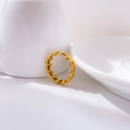 Nahaufnahme eines goldenen, grob geflochtenen Rings auf einer weißen Keramiktasse - US 6 / Federring