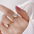 Bague cœur élégante en or avec zircons violets et verts portée par un modèle - US 7 / Grande Zircone de Coeur