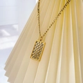 Gros plan du pendentif en damier doré avec zircons sur une chaîne de style Figaro - Carré à Damier Zircone / Doré