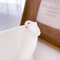 Détail macro d'une bague en perles lustrées avec une bille plaquée or sur un support - US 6 / Boule d'Or Unique avec Plusieurs Perles