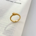 Primer plano de anillo de serpiente dorado con escamas detalladas sobre fondo de libro retro - US 6 / Estilo de Serpiente Cerrada de una Sola Capa / Dorado